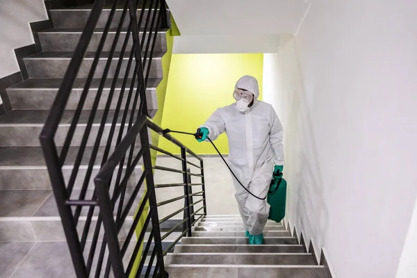 コロナウイルス コビットから建物内の保護スーツとマスク滅菌手すりの労働者 — ストック写真