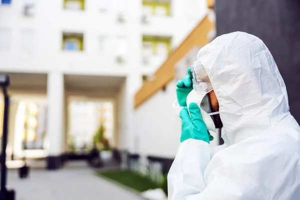 Profile of man in protective sterile uniform putting mask while standing outdoors.