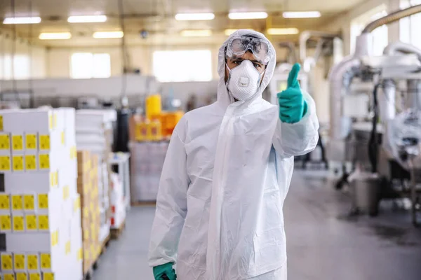 身穿防护服 戴口罩 戴手套的男子站在食品生产厂 竖起大拇指 他刚刚用Covid Corona病毒对整个设施进行了消毒 — 图库照片
