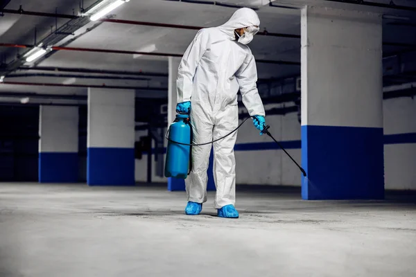 保護滅菌スーツとマスクの労働者の完全な長さコロナウイルス Covid 19から地下ガレージを消毒 — ストック写真