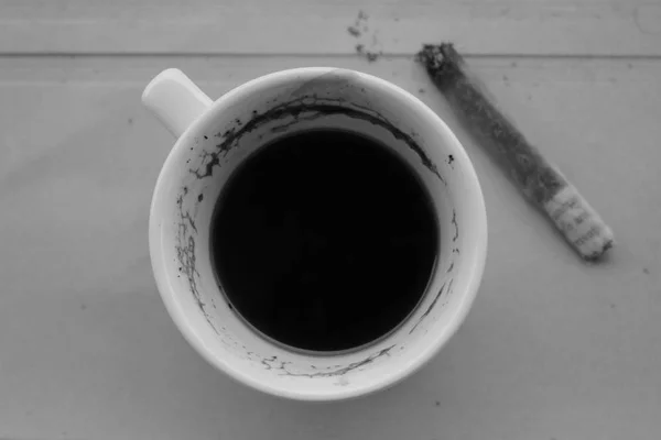 Vista superior primer plano taza de café y cigarrillo blanco negro — Foto de Stock