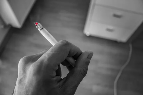 Man holding lit cigarette in his hand. Black and white — Stock Photo, Image