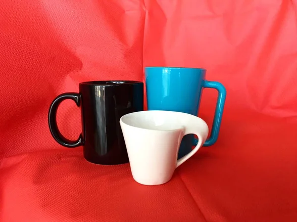 Drie kopjes voor koffie of thee met rode stof achtergrond — Stockfoto