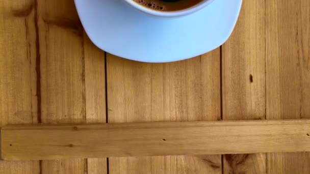 木製のテーブルにコーヒーをブラックで白いカップ — ストック動画