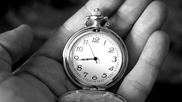 Old antique pocket watch showing time being held in hand. Close up shot black and white photography