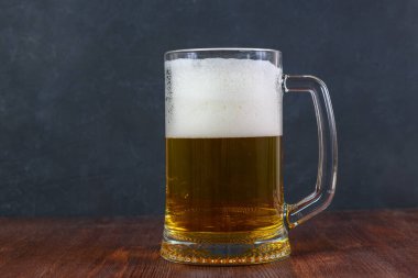 Bardakta bira. Koyu arkaplanda, ahşap masada su damlaları..