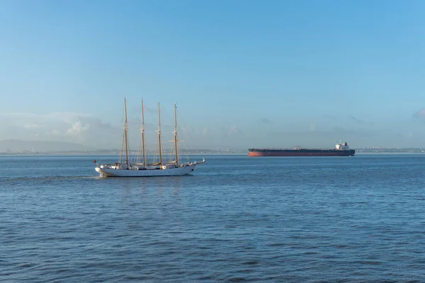 Four masts sailing ship and cargo ship at sea