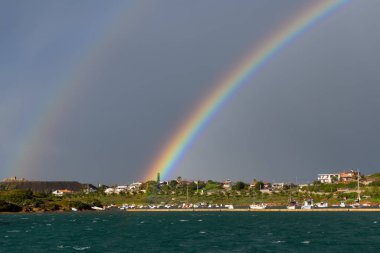 Yelkenli ve motorlu marinada fırtınalı gökyüzünde güzel gökkuşağı