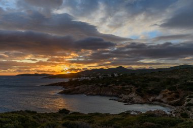 Güzel kayalık sahil şeridi ve gün batımında mavi deniz.