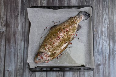 Fresh raw trout with salt and pepper on wooden background