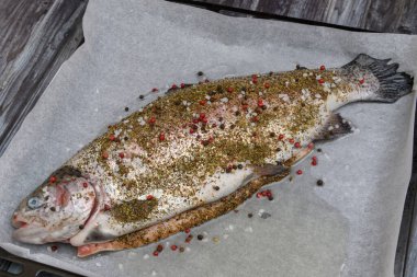Fresh raw trout with salt and pepper on wooden background