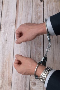 Arrested businessman or official in handcuffs. Corruption or economic crime concept.