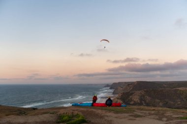 Paraglider flying over thesea shore at sunset. Paragliding sport concept.