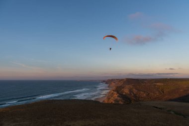 Paraglider flying over thesea shore at sunset. Paragliding sport concept.