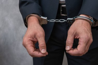 Arrested businessman or official in handcuffs. Corruption or economic crime concept.