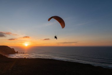 Paraglider flying over thesea shore at sunset. Paragliding sport concept.