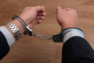 Arrested businessman or official in handcuffs. Corruption or economic crime concept.