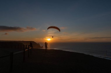 Paraglider flying over thesea shore at sunset. Paragliding sport concept.