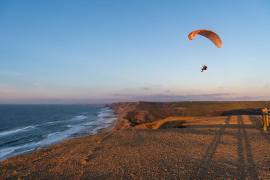 Paraglider flying over thesea shore at sunset. Paragliding sport concept.