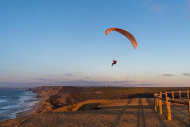 Paraglider flying over thesea shore at sunset. Paragliding sport concept.