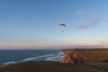 Paraglider flying over thesea shore at sunset. Paragliding sport concept.