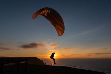 Paraglider flying over thesea shore at sunset. Paragliding sport concept.
