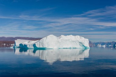 Grönland fiyordunda sakin sularda yansıyan buzdağı. Güneşli bir hava. Altın saat.