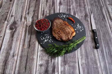 Koyu ahşap arka planda tuzlu ve biberli ızgara biftek pirzolası.