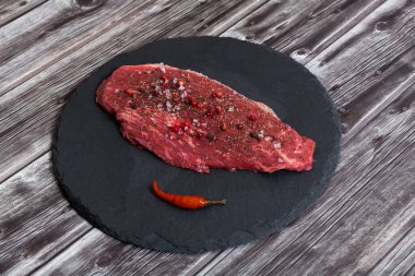 Koyu arka planda çiğ mermer et ve baharatlar.