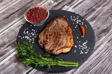 Koyu ahşap arka planda tuzlu ve biberli ızgara biftek pirzolası.