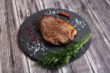 Koyu ahşap arka planda tuzlu ve biberli ızgara biftek pirzolası.