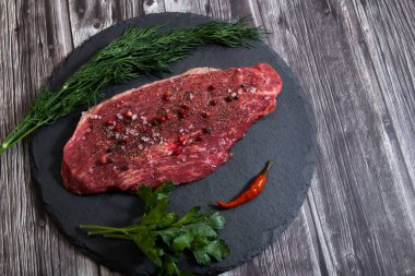 Koyu arka planda çiğ mermer et ve baharatlar.