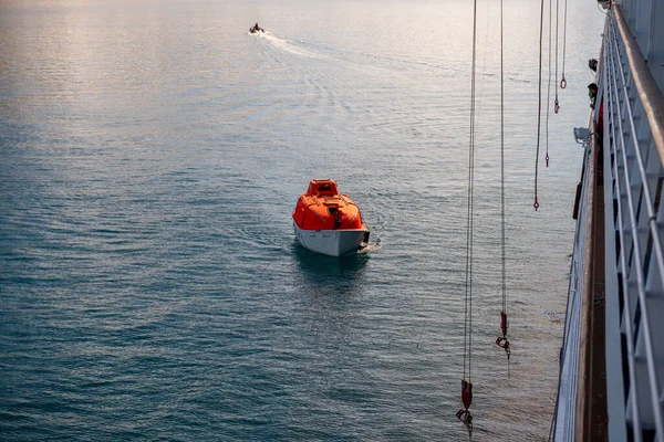 北極海の水の中でオレンジ色の救命ボートを操縦 スヴァールバル 船の訓練を放棄する 救命艇の訓練 ボードドリルの男 — ストック写真