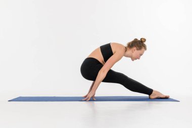 Beyaz arka planda yoga yapan çekici genç bir kadın..