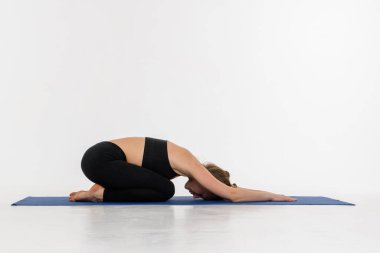 Beyaz arka planda yoga yapan çekici bir genç kadın. Çocuk Duruşu, Balasana.