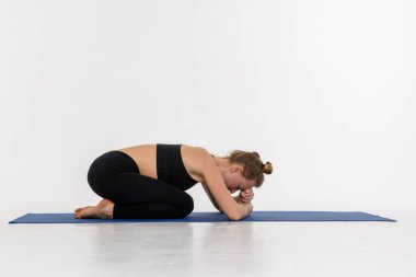 Beyaz arka planda yoga yapan çekici bir genç kadın. Çocuk Duruşu, Balasana.