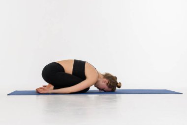 Beyaz arka planda yoga yapan çekici bir genç kadın. Çocuk Duruşu, Balasana.