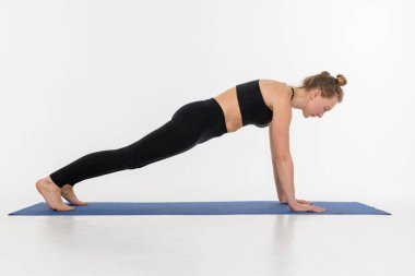 Beyaz arka planda yoga yapan çekici genç bir kadın..