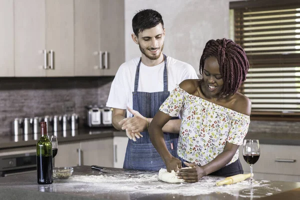 Feliz casal de raça mista amassar massa juntos na cozinha — Fotografia de Stock