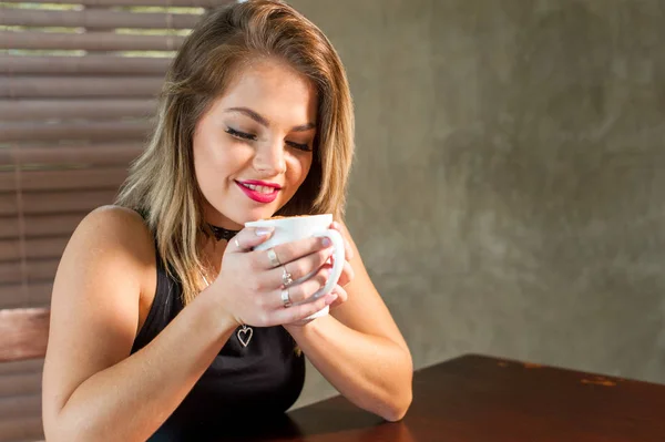 Attractive woman drinking a hot beverage — Stock Photo, Image