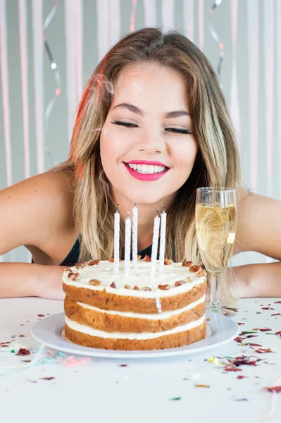 Chica bonita mirando velas encendidas en pastel de cumpleaños para celebrat Fotos de stock