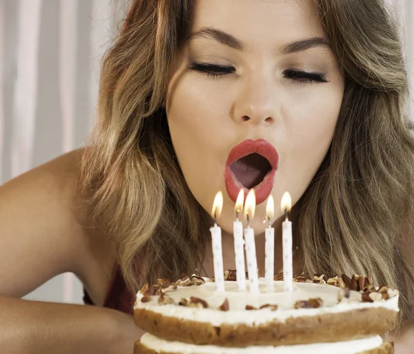 Joven atractiva cumpleañera soplando velas en un cak —  Fotos de Stock