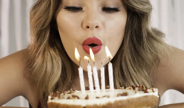 Joven atractiva cumpleañera soplando velas en un cak Imágenes de stock libres de derechos