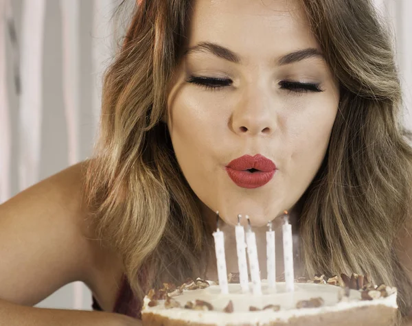 Joven atractiva cumpleañera soplando velas en un pastel —  Fotos de Stock
