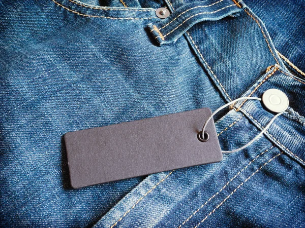 Label gray price tag mockup on blue jeans.