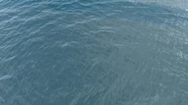 Mavi denizin yüksek irtifasından kuş bakışı görüş. Su yüzeyi dokusunun arka planı. Güneşli bir günde dalgalı suyun havadan görünüşü.