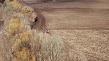 İlkbaharda kırsal bölgedeki tarım sektörünün hava görüntüsü. Çiftçi tarlayı sürerek ekin ekmeye hazırlanıyor. Traktör, bitki tarımı için ilkbaharda çiftlikteki toprağı işliyor..