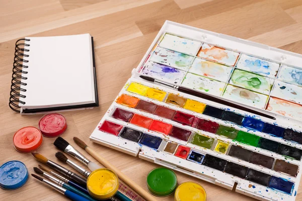 Empty sketchbook on chalk board with art supplies around. Mock up for illustration or art. — Stock Photo, Image