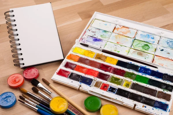 Empty sketchbook on wood table with art supplies around. Mock up for illustration or art. — Stock Photo, Image