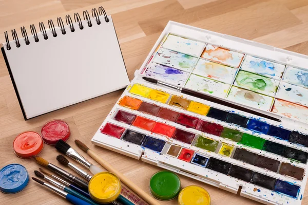 Empty sketchbook on wood table with art supplies around. Mock up for illustration or art. — Stock Photo, Image